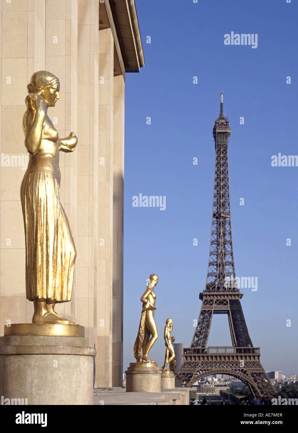 Three of eight gilded gold statues at place du Trocadéro on terrace of the Rights of Man with Eiffel Tower landmark structure beyond Paris France EU Stock Photo