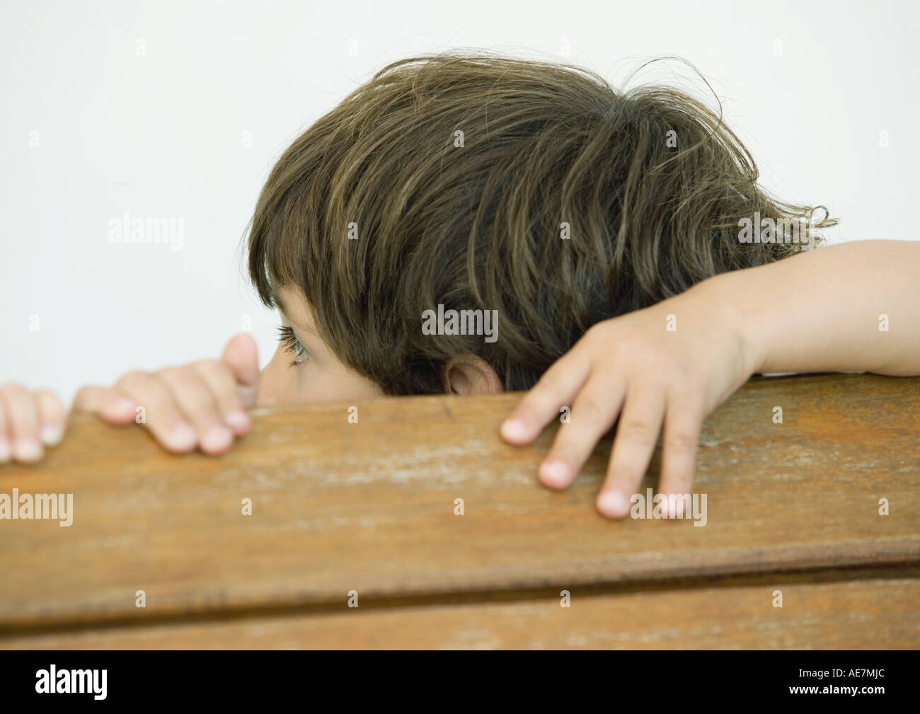Boy with hands on edge of wooden plank, turning away Stock Photo