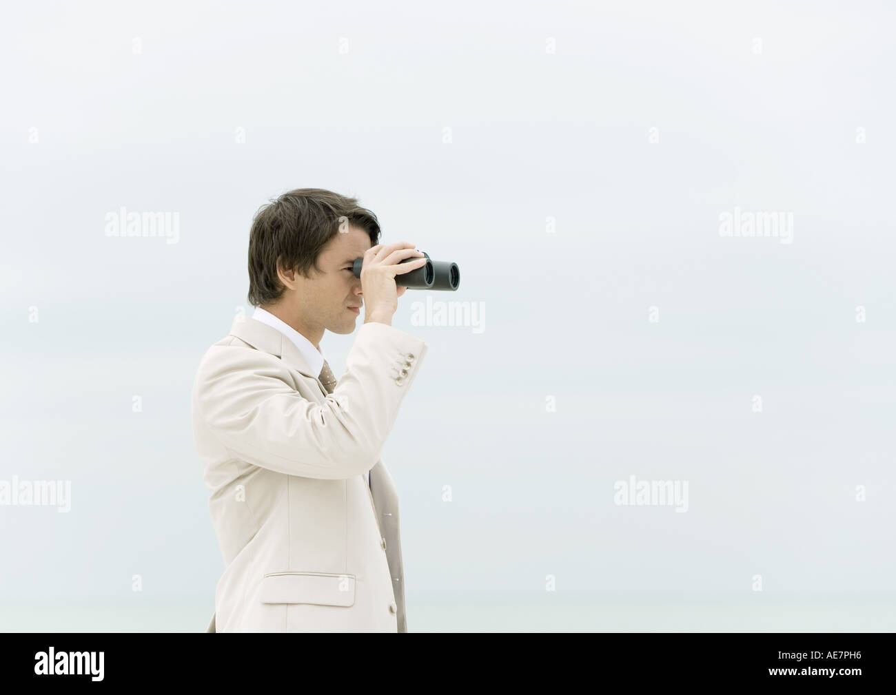 Businessman using binoculars, sea in background Stock Photo