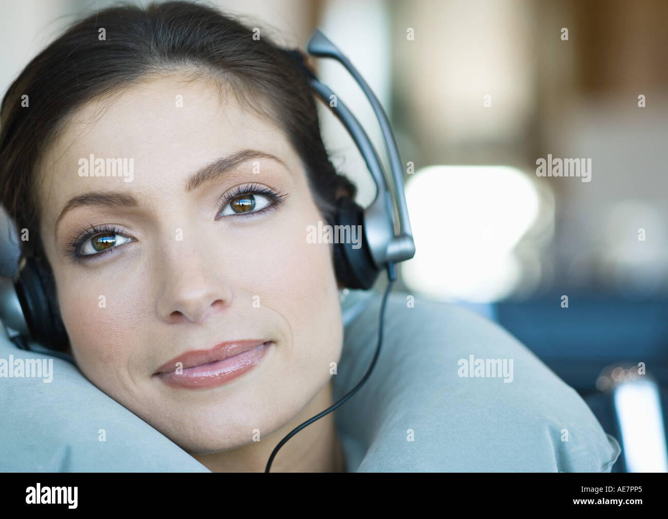 Woman wearing headphones and using neck pillow Stock Photo