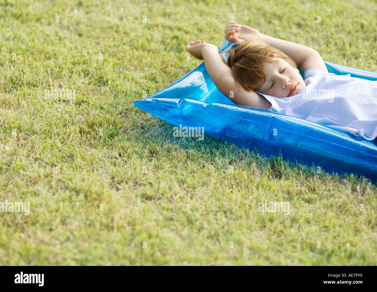 Little boy sleeping on inflatable raft, on grass Stock Photo