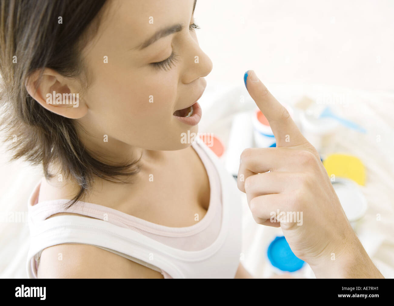 Man's finger reaching towards woman's nose with drop of paint Stock Photo