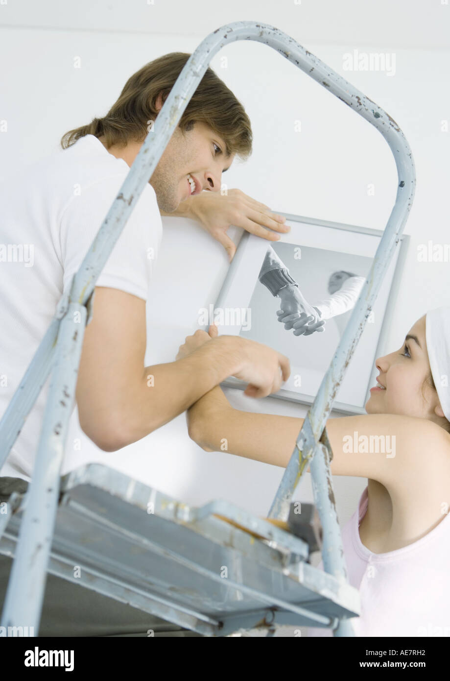 Couple hanging up photo on wall Stock Photo