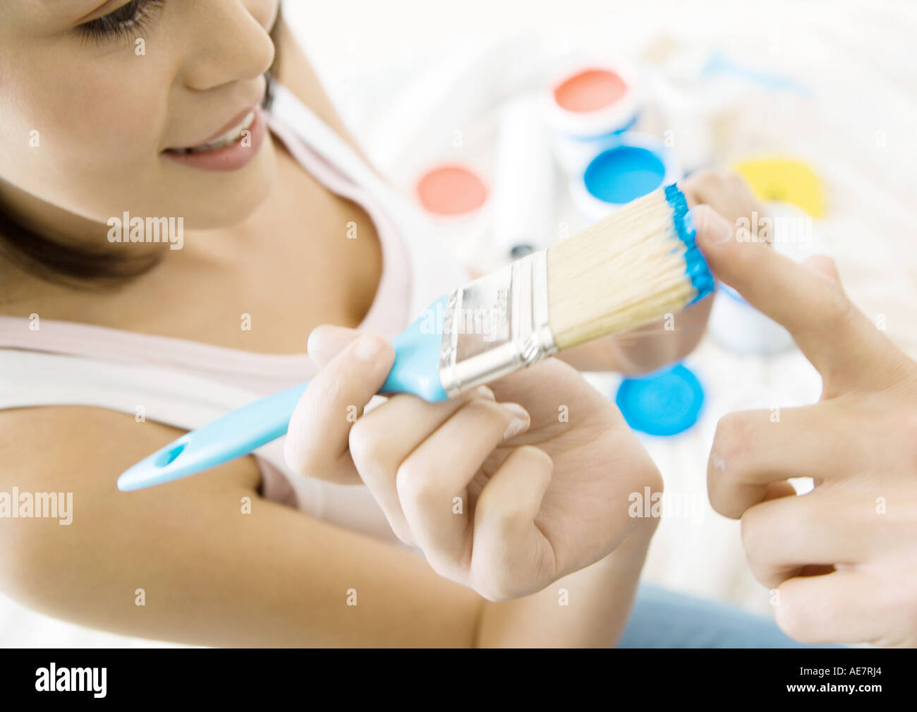 Woman holding up paintbrush to man's finger Stock Photo