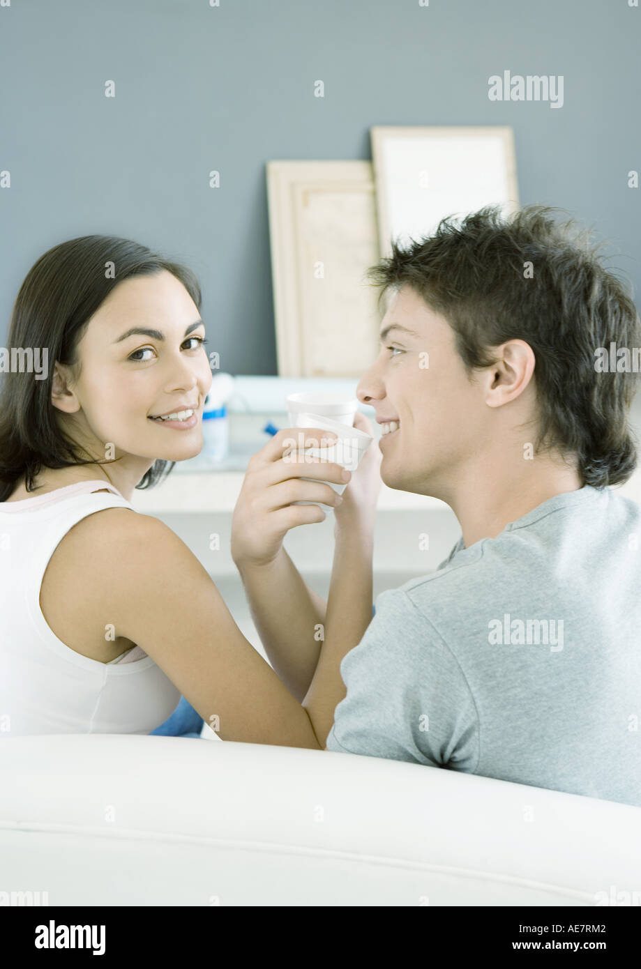 Couple sitting with arms linked, about to drink Stock Photo