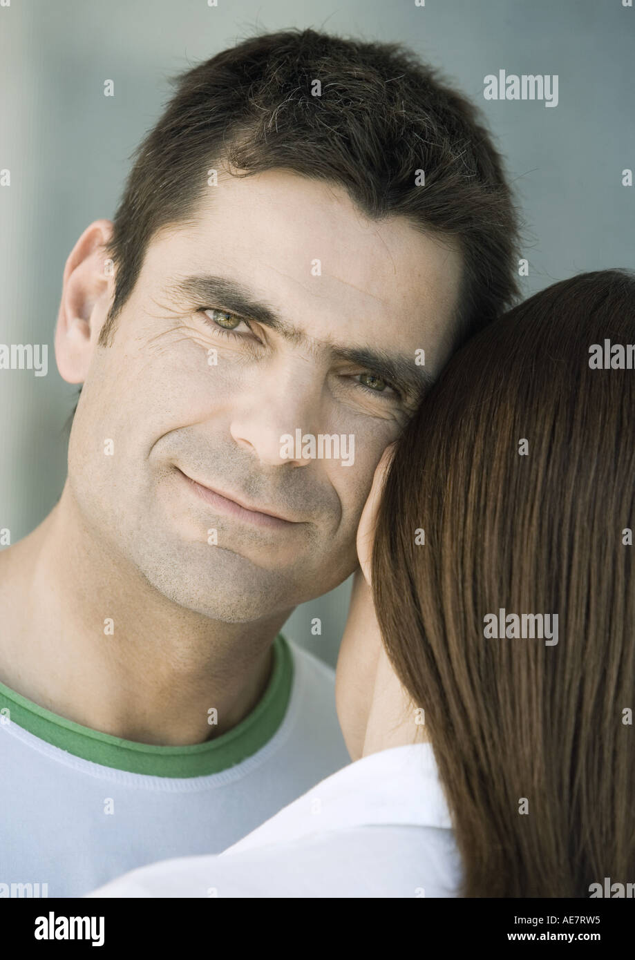 Man resting head against woman's head, smiling, partial view Stock Photo