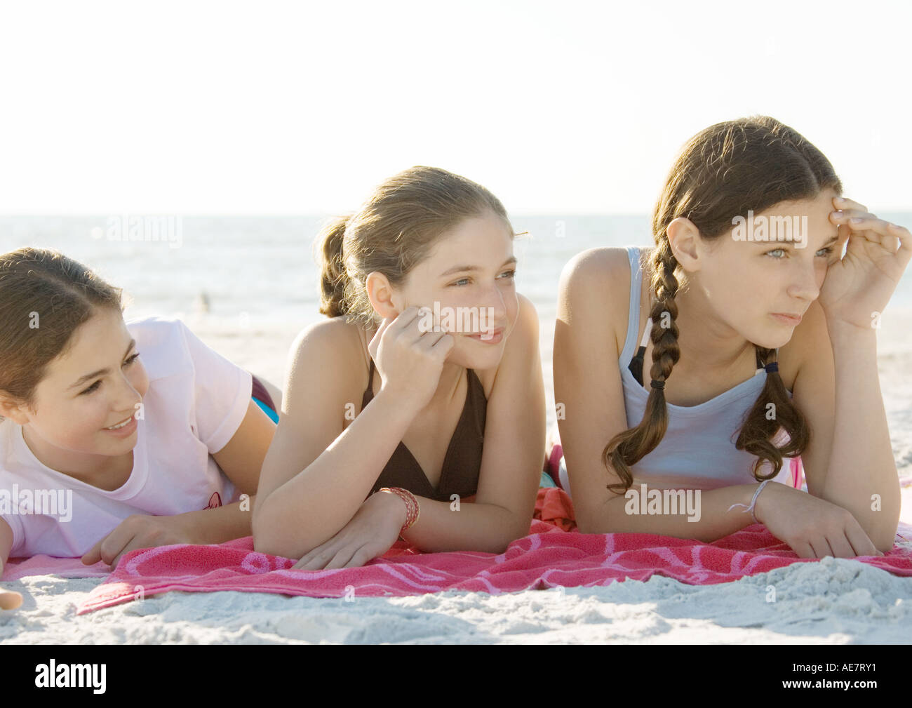 Three preteen girls lying on beach Stock Photo