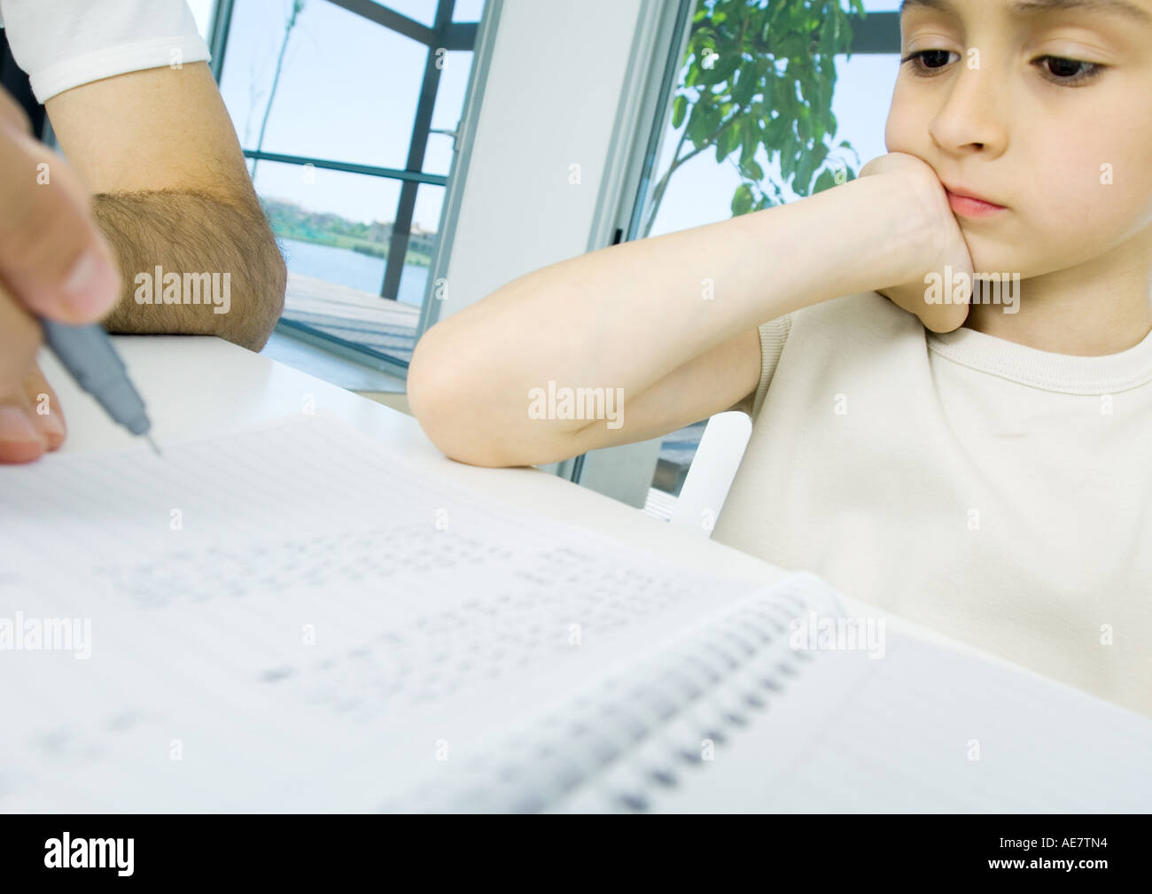 Boy doing homework with father's help, cropped Stock Photo