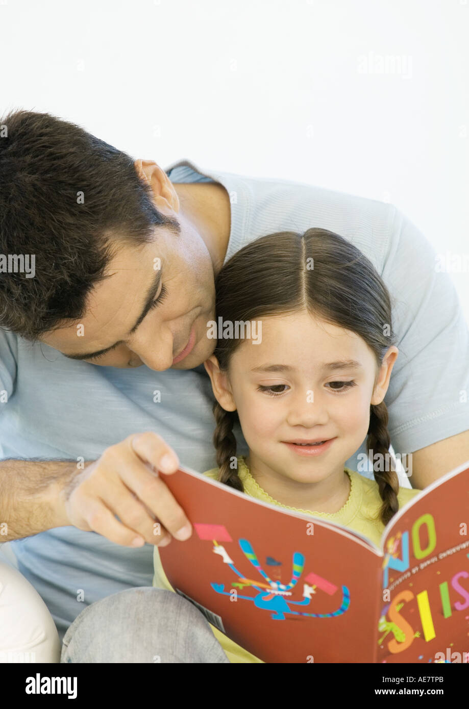 Father and daughter reading book together Stock Photo