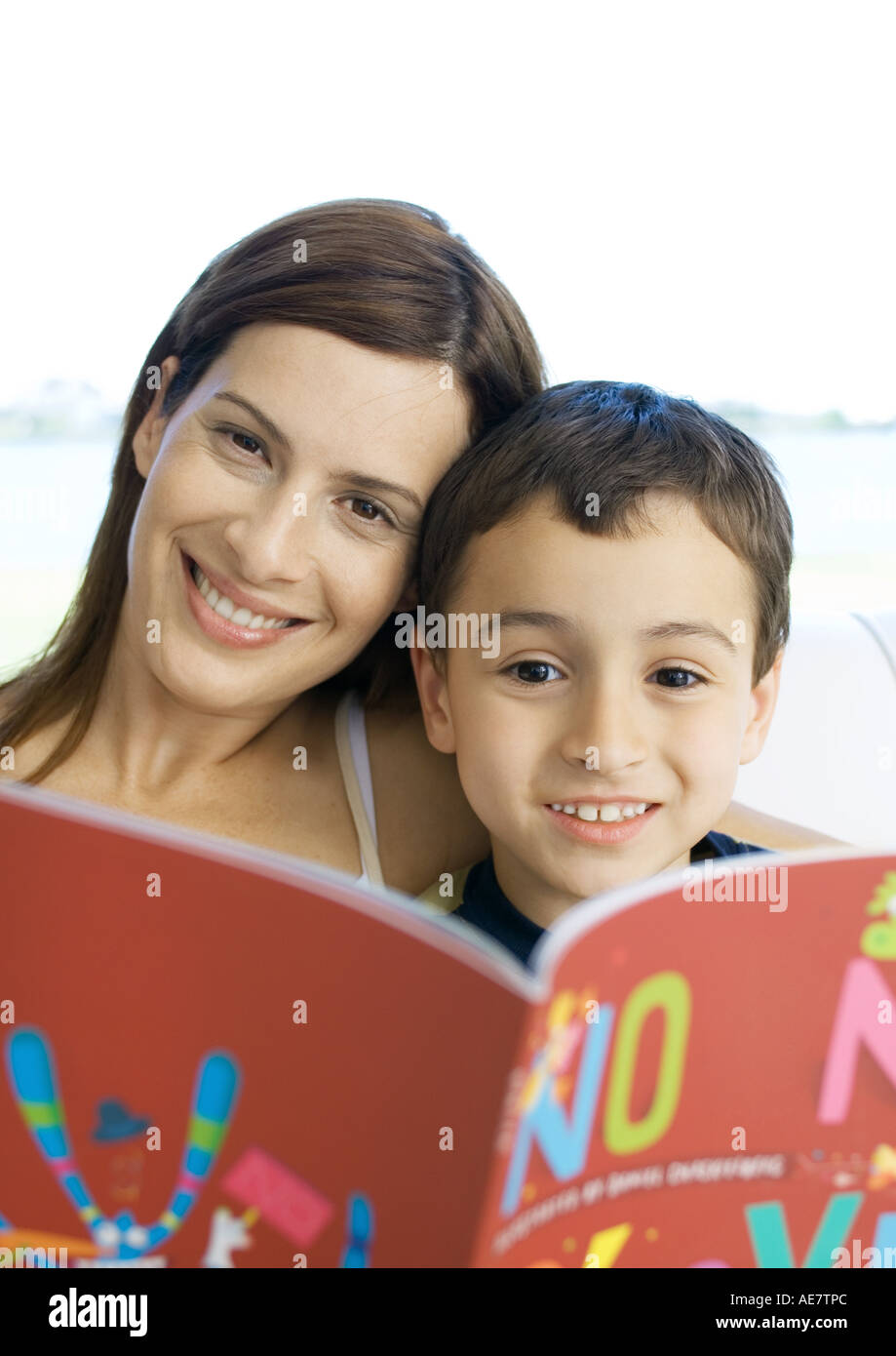 Mother and son with book, smiling at camera Stock Photo