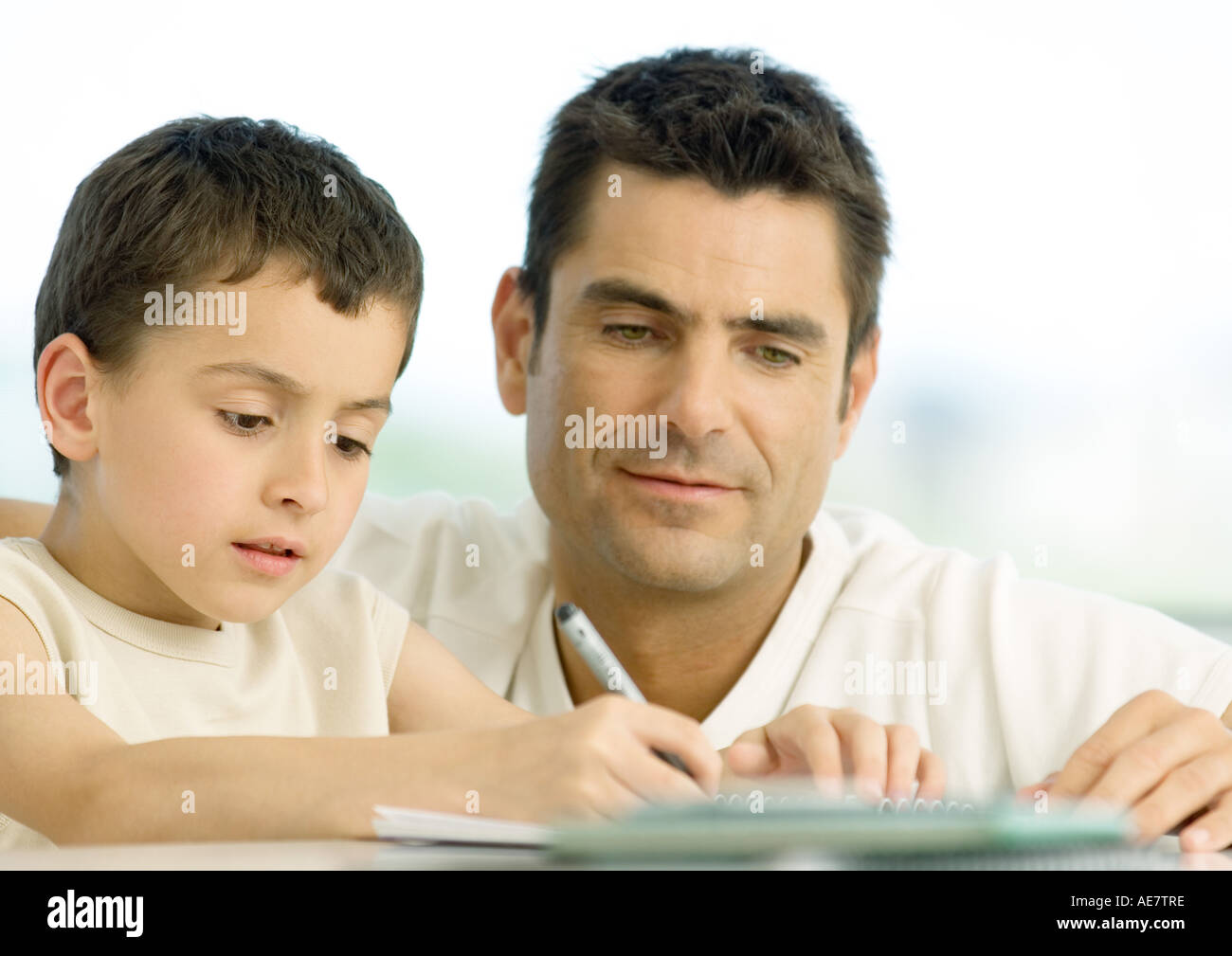 Boy doing homework with father's help, cropped Stock Photo