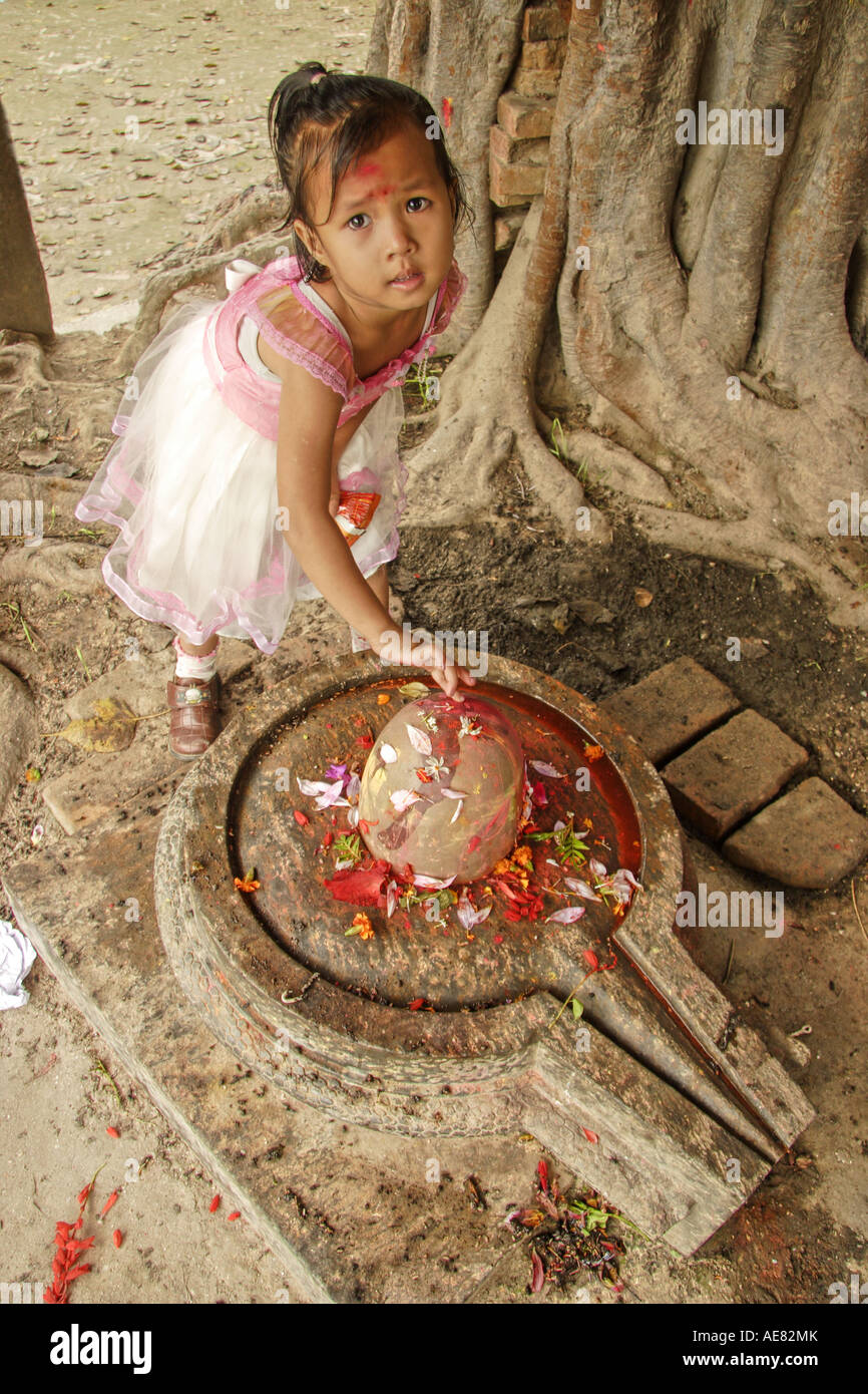 Young Hindu girl worships the linga-yoni figure (represents male and female unity) Stock Photo