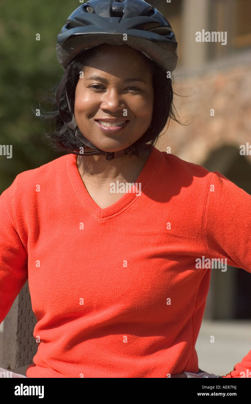 A young 20 something African American Woman exercising outside dressed in a bike helmet and bright orange shirt. Stock Photo