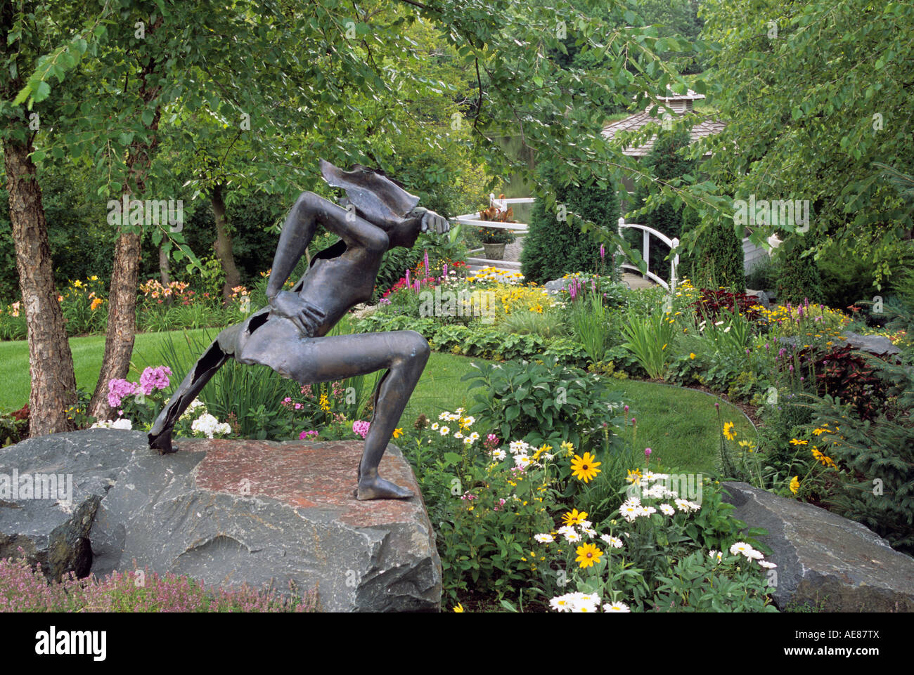 BRONZE SCULPTURE IN MINNESOTA GARDEN SURROUNDED BY PERENNIALS AND RIVER