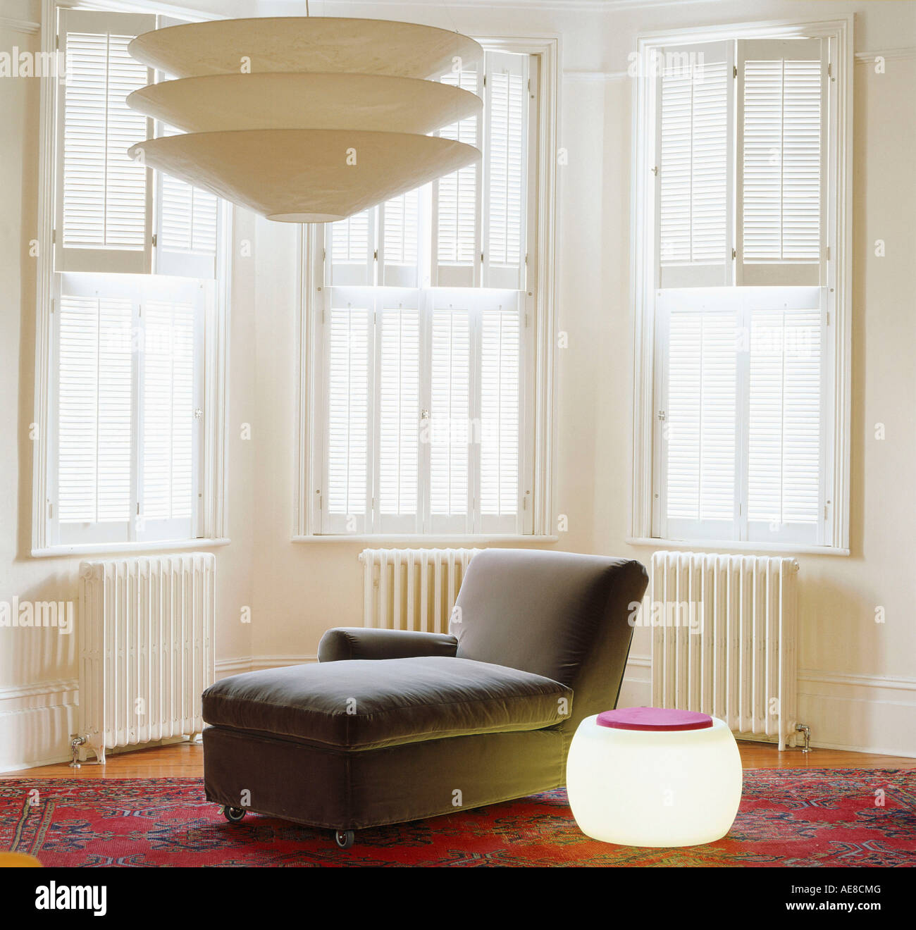 Daybed and modern lighting with shuttered bay window in background