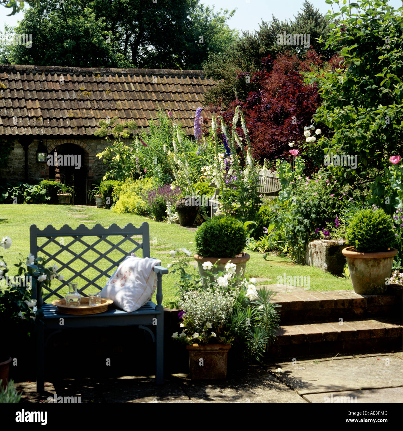 English country garden lawn with stone patio and flowerbed Stock Photo