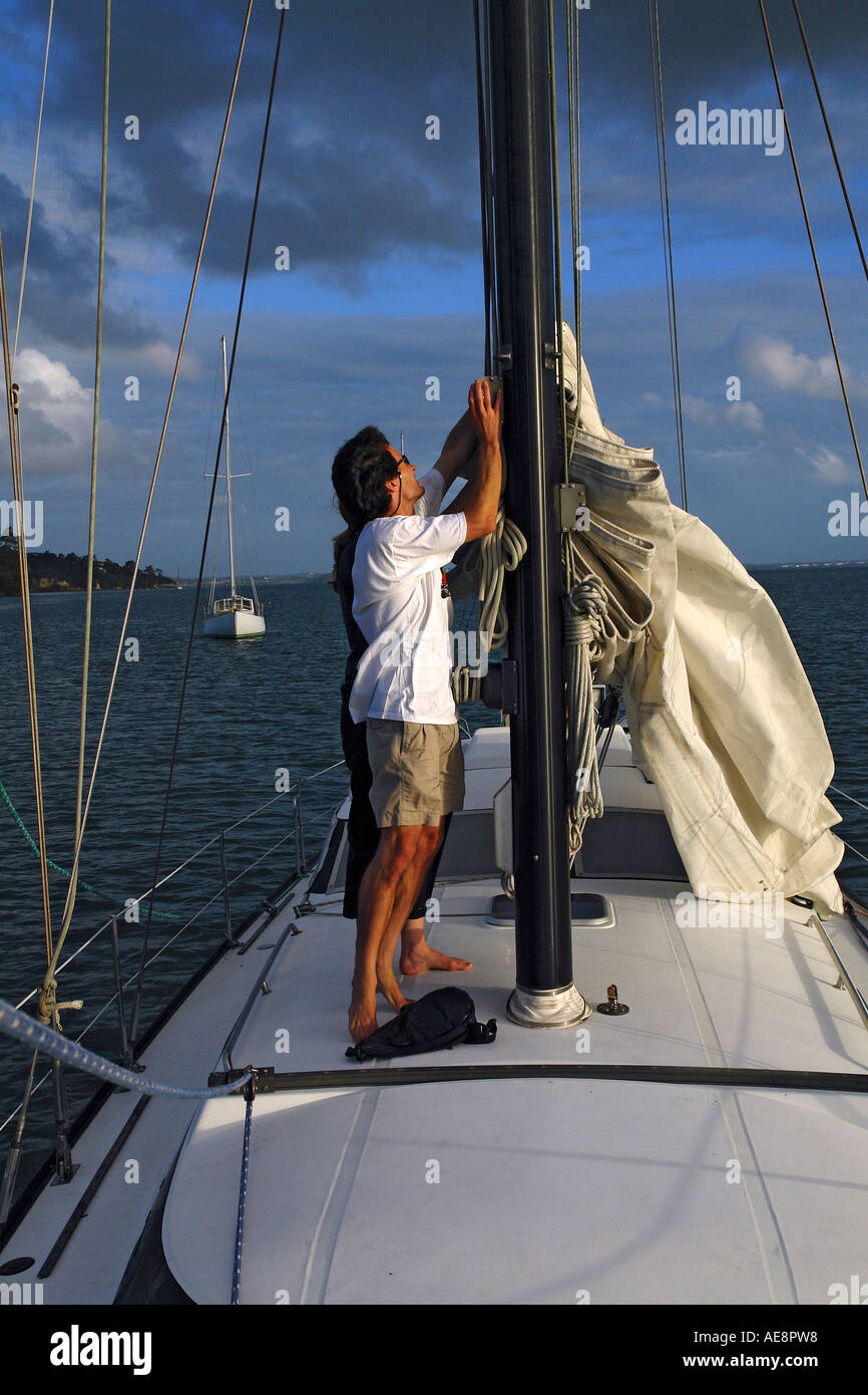 Setting sail couple hoisting the mainsail on a sailing yacht Stock