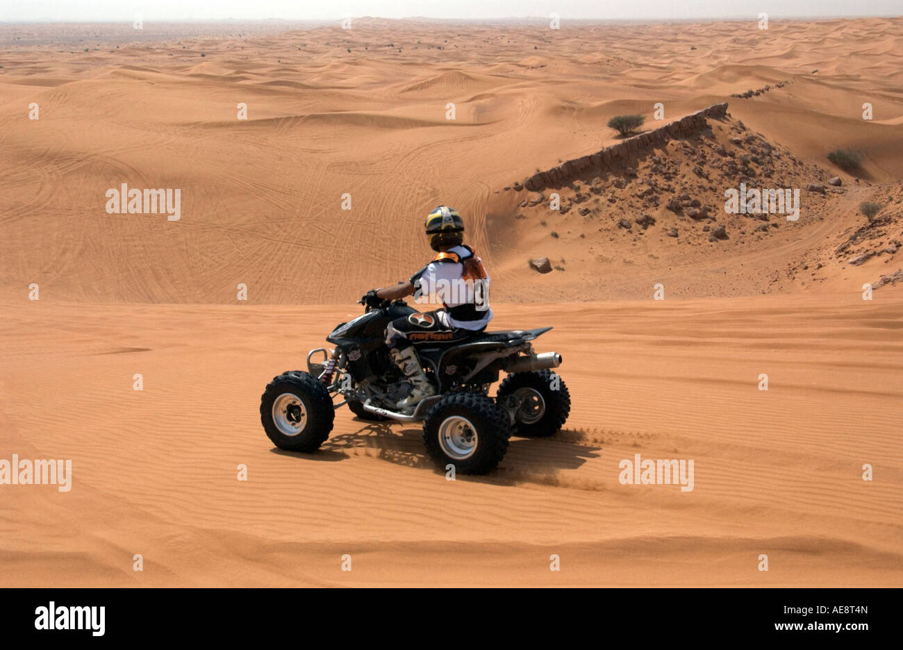 Rider on quadbike on sand dune above Dubai desert Stock Photo
