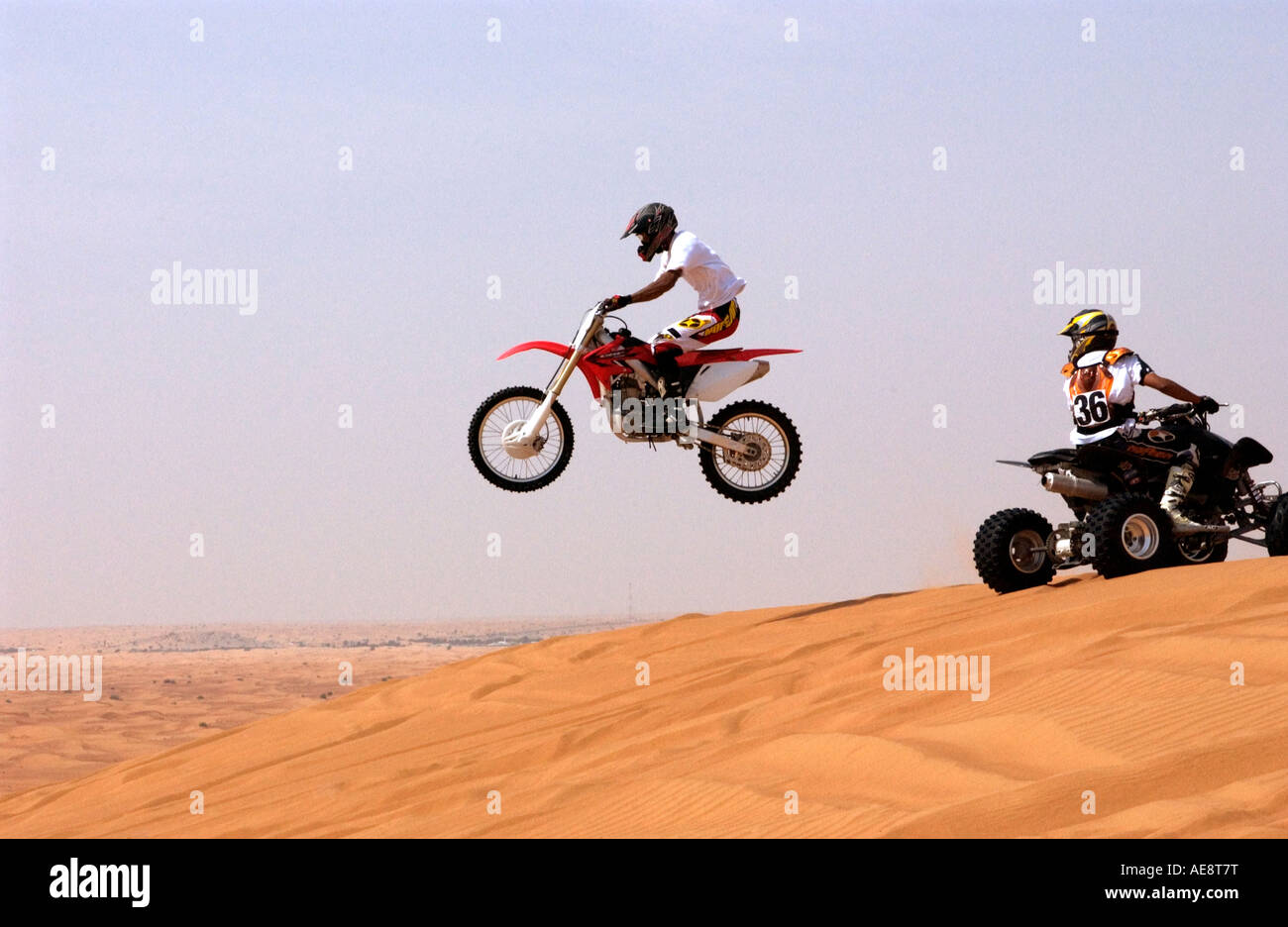 Quadbike speeding off the edge of a Dubai desert dune Stock Photo