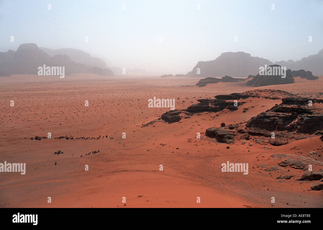 Red sand floor of the desert with rocky outcrops called Jebels in the distance Wadi Rum Jordan Stock Photo