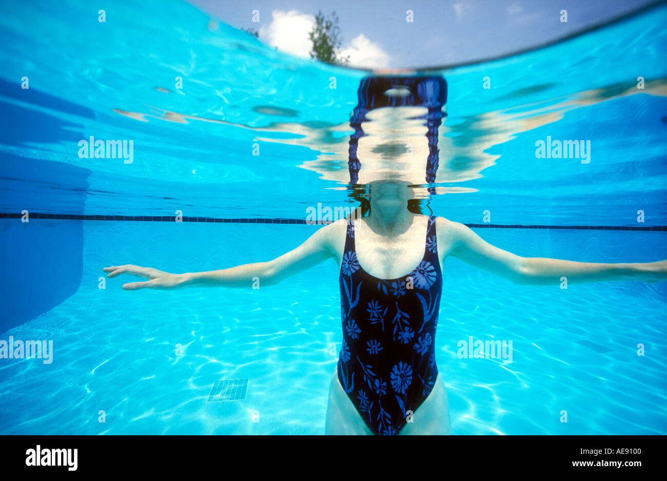 Underwater view of woman in swimsuit in swimming pool Model released