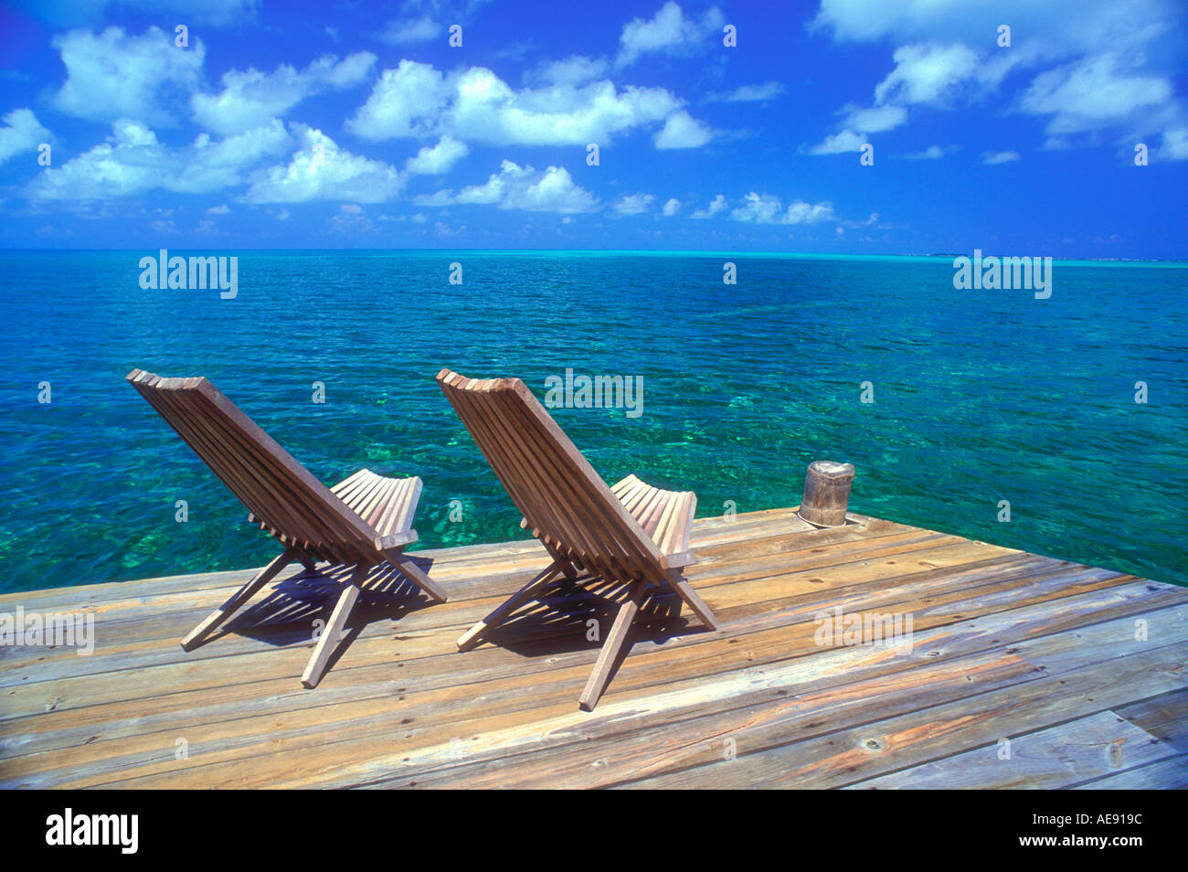 Two wooden deck chairs facing out over sea towards horizon in the ...
