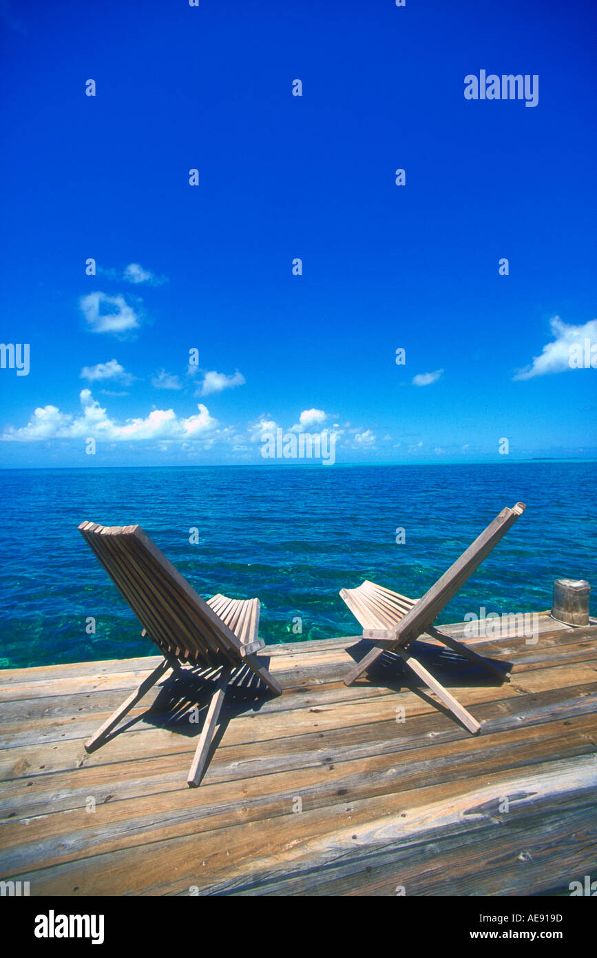 Two wooden deck chairs facing out over sea towards horizon in the ...