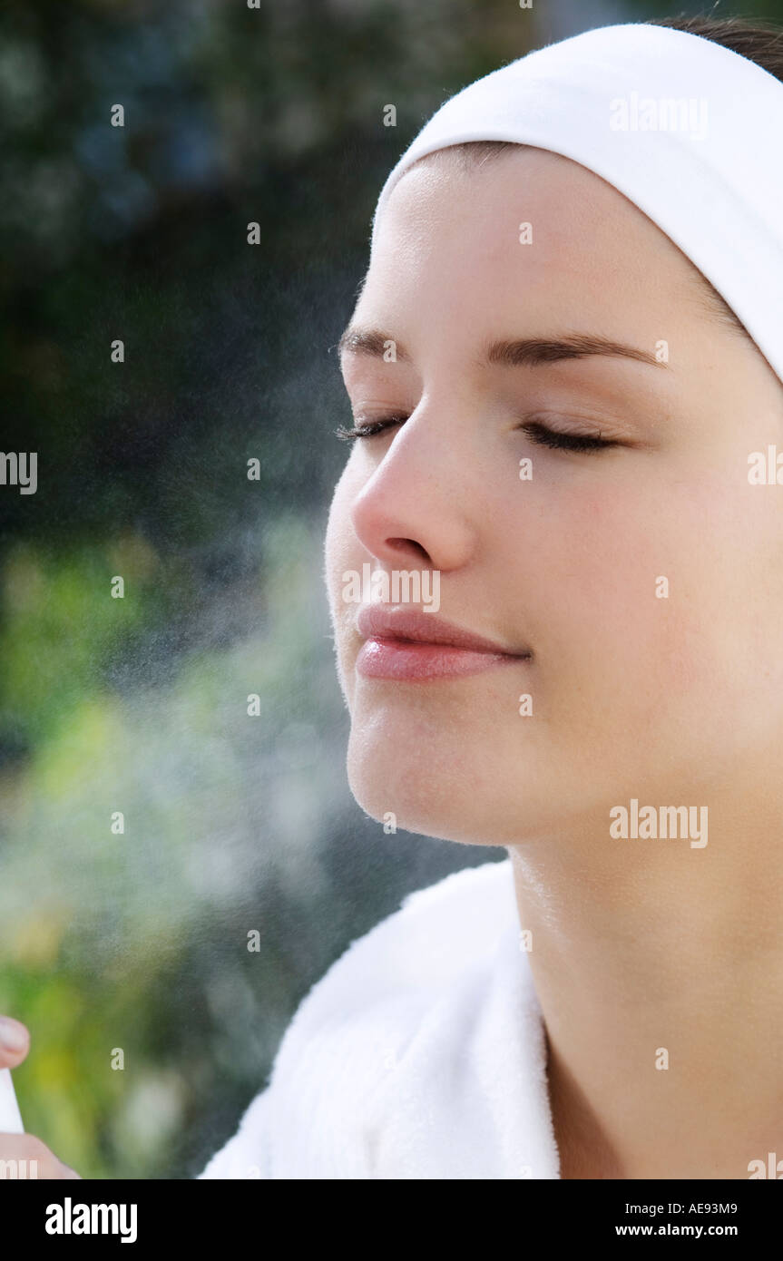 Woman spraying water on her face, Indoors Stock Photo Alamy