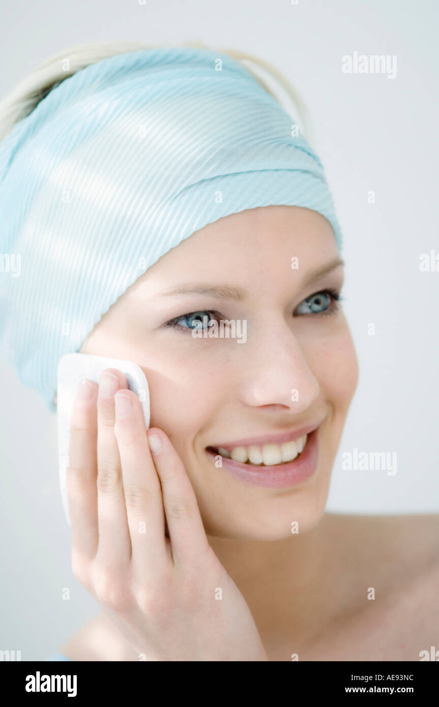 Young Woman face with make up, holding a cleansing cotton on her cheek (studio) Stock Photo