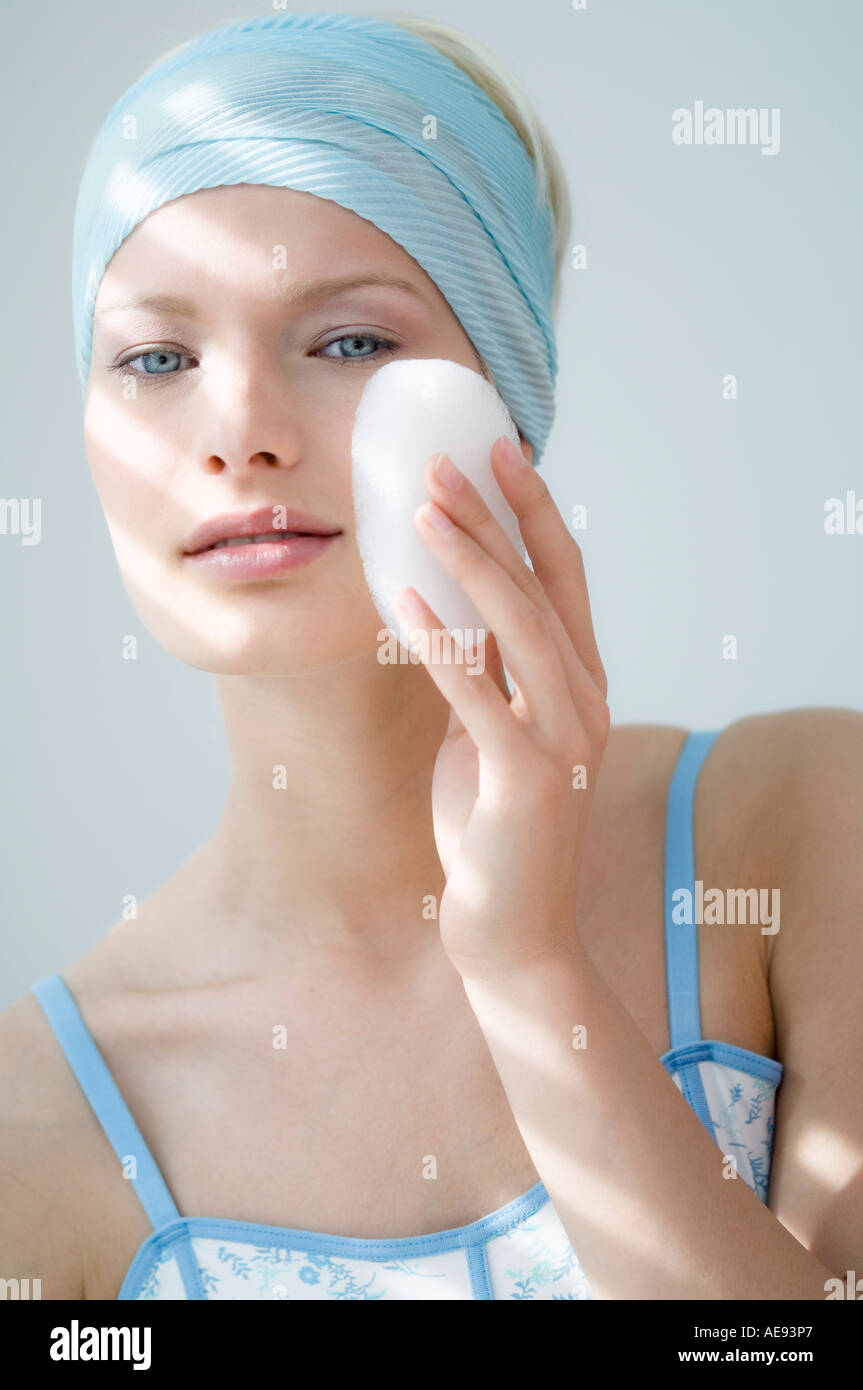 Young Woman face with make up, holding a bath sponge on her cheek