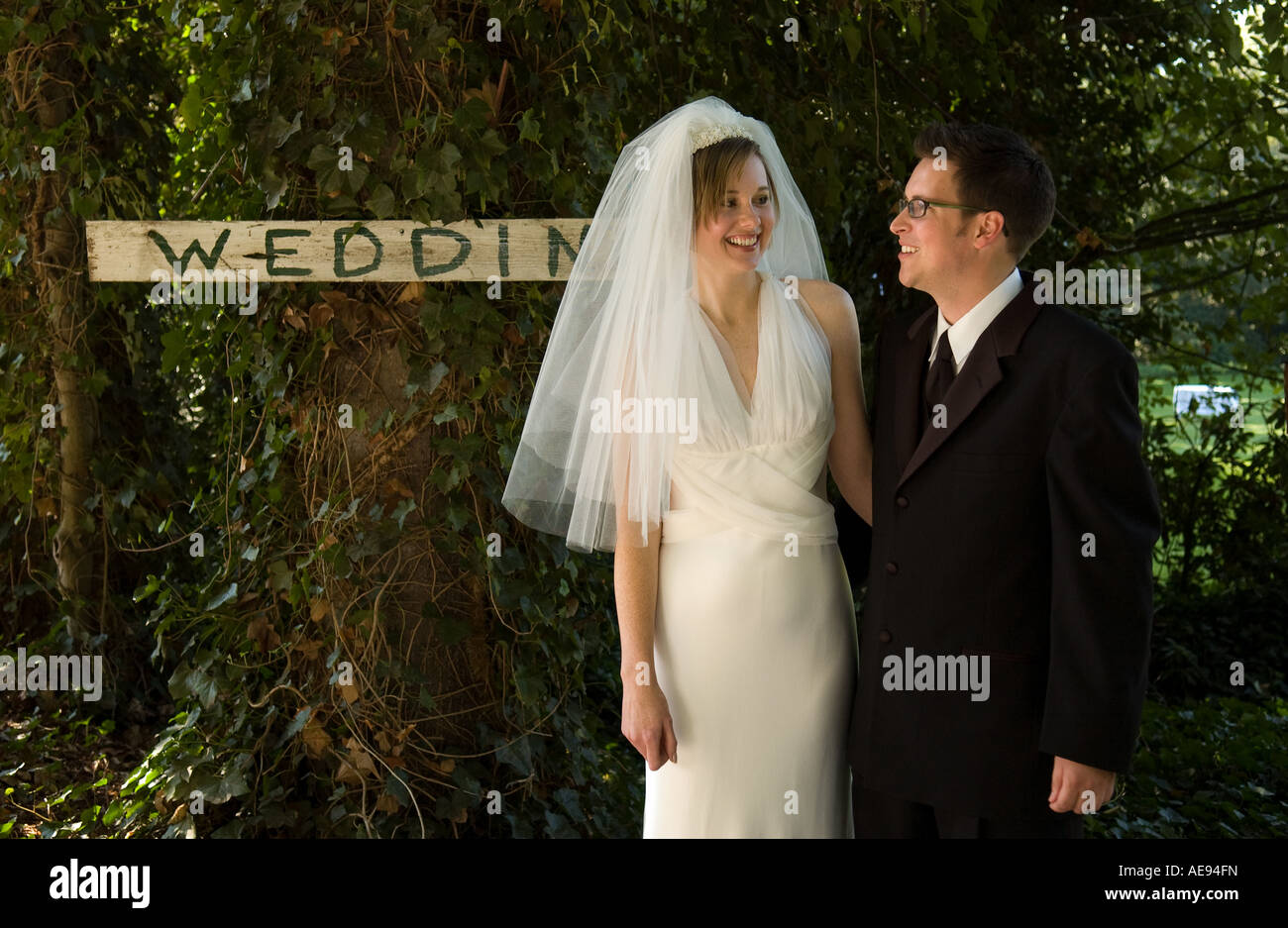 Bride and her groom standing next to a wedding sign Stock Photo - Alamy