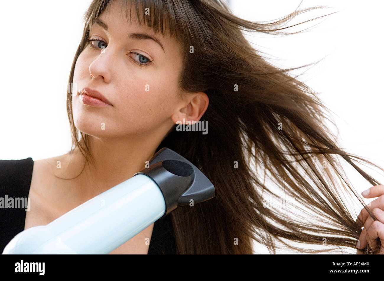 Portrait of a young woman using a hair drier Stock Photo - Alamy
