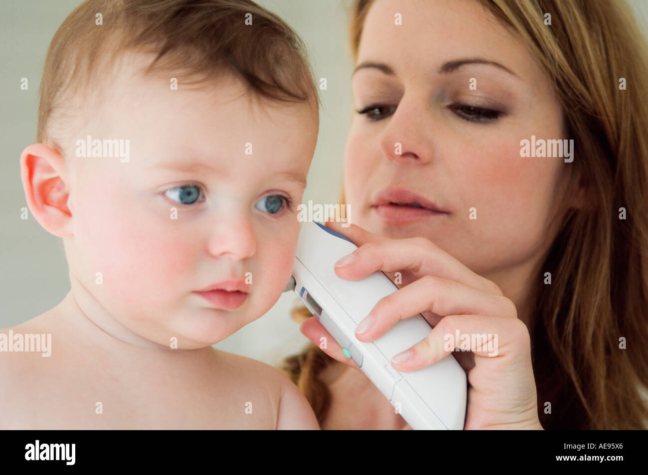 Mother taking her baby's temperature with an earthermometer Stock