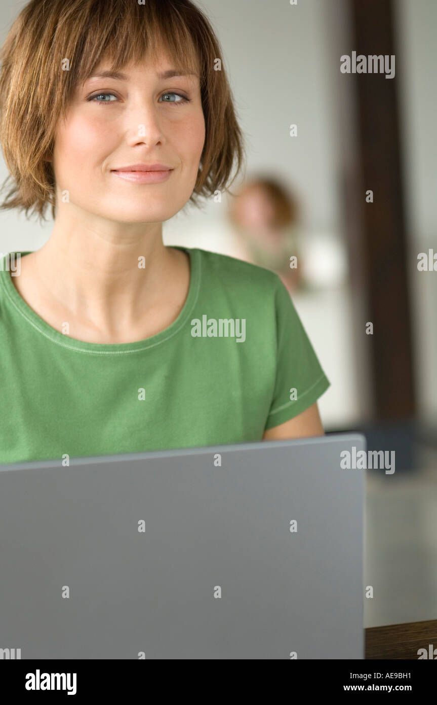 Young woman using laptop computer, looking at the camera Stock Photo