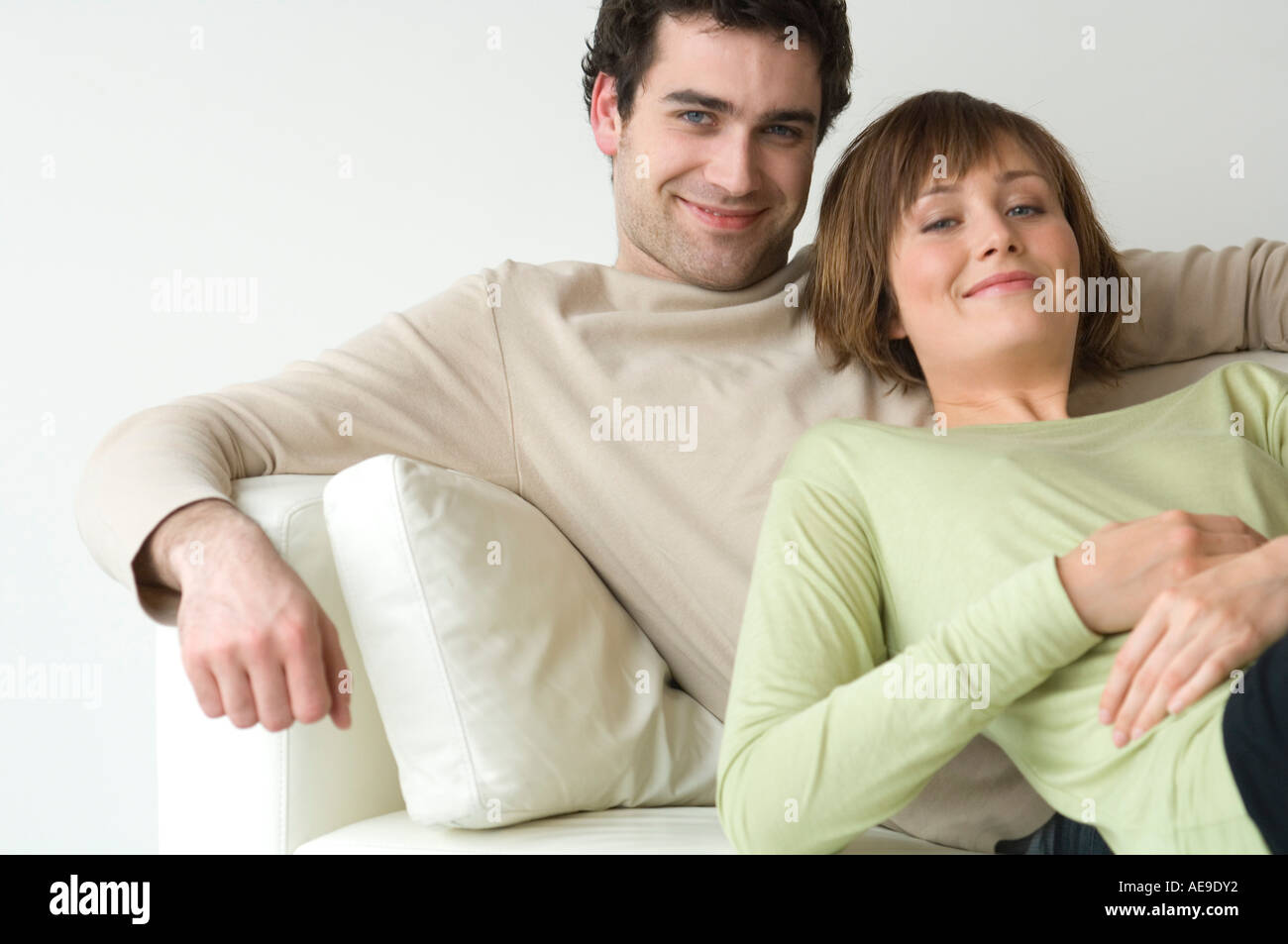 Couple lying on a sofa, smiling for the camera Stock Photo