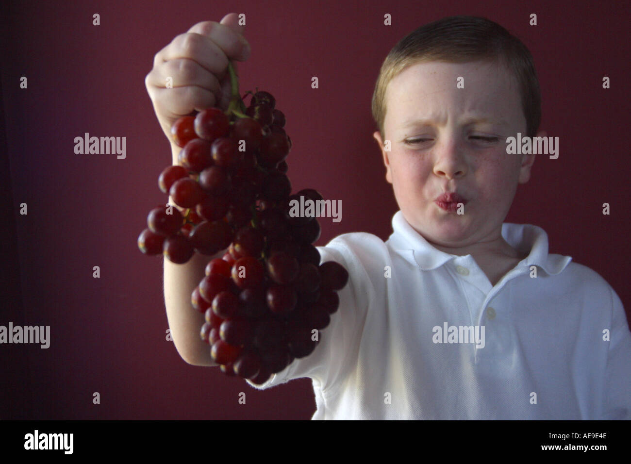 Boy making face at grapes Stock Photo