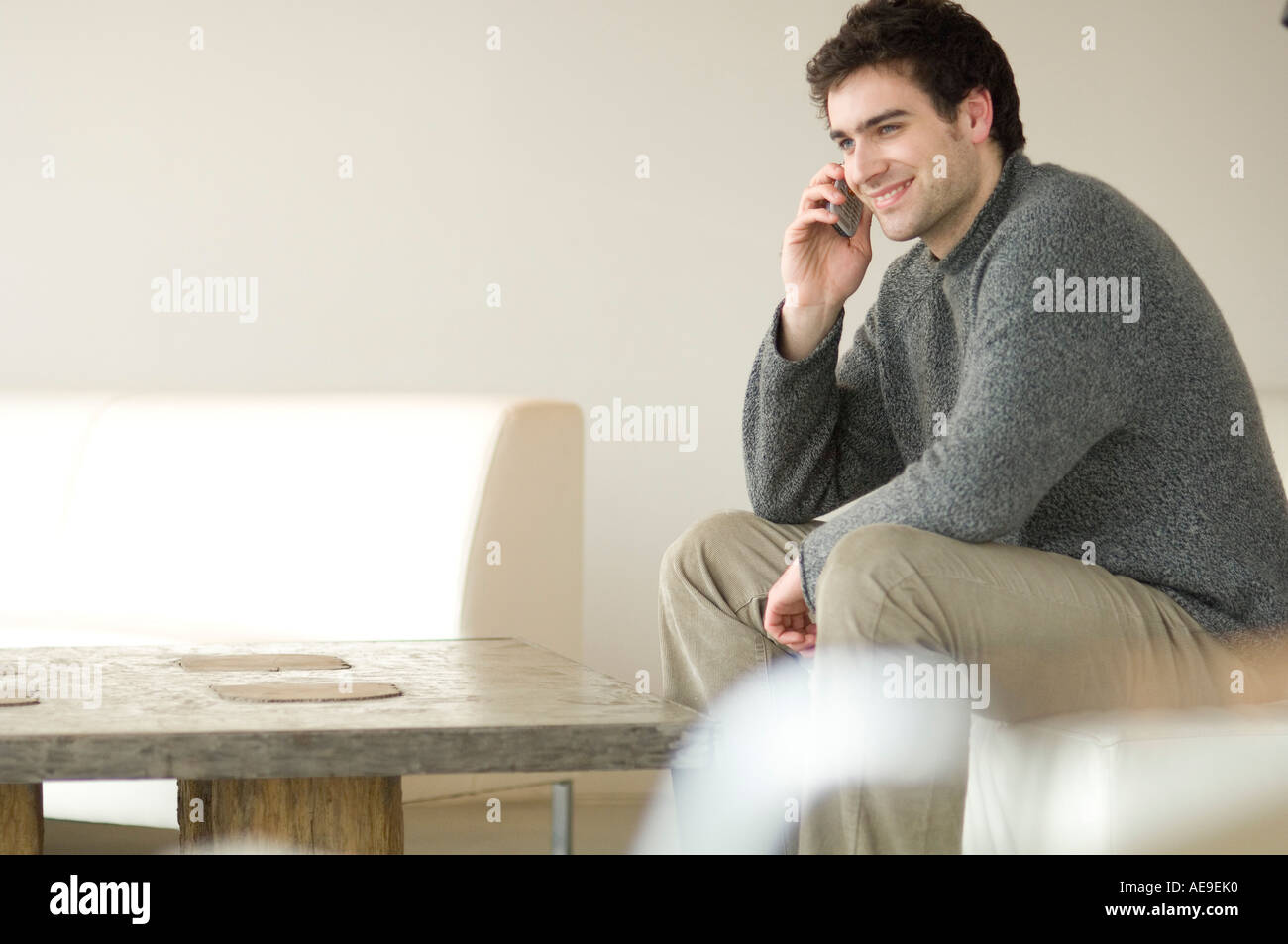 Man sitting on a sofa using a mobile phone Stock Photo