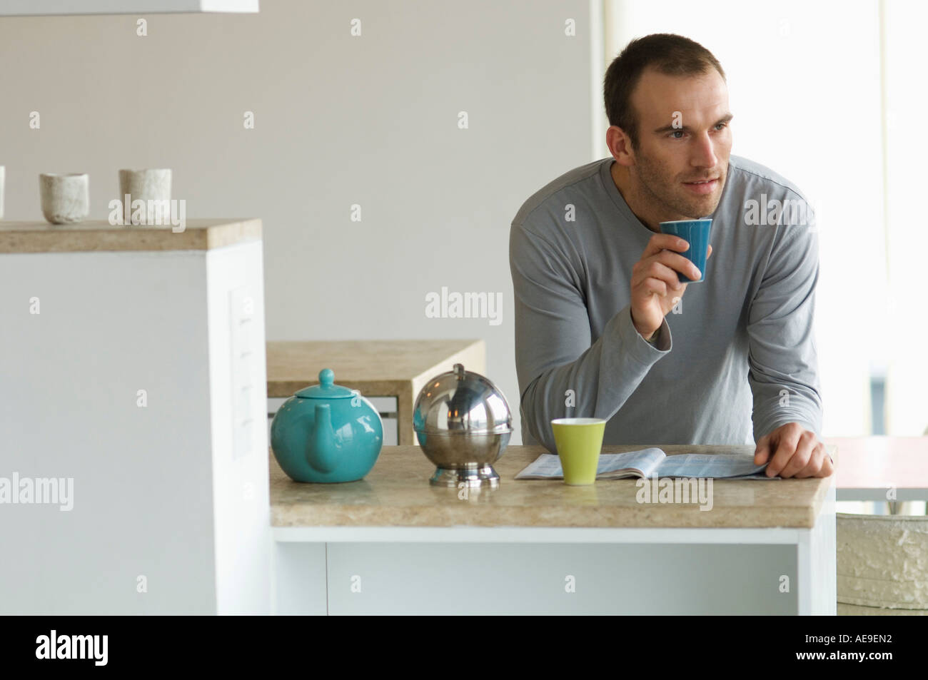 Man standing inthe kitchen, holding glass Stock Photo