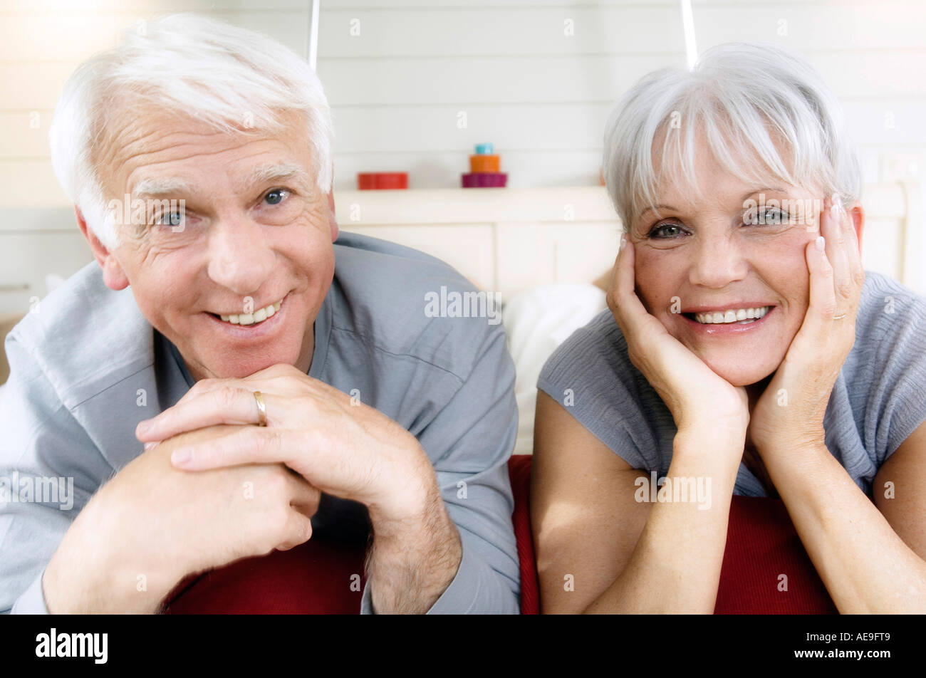 Senior couple lying on bed, smiling for the camera Stock Photo