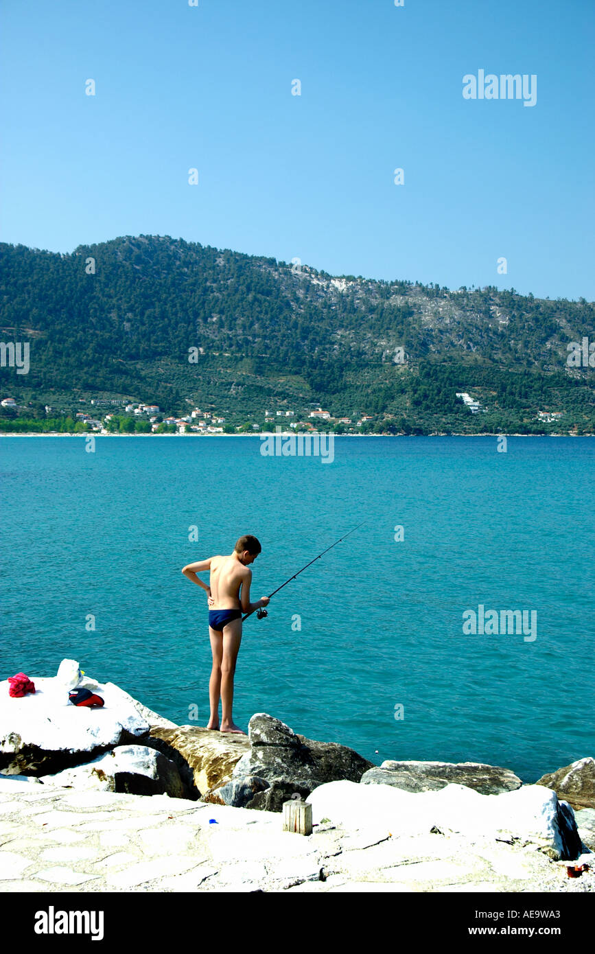 Boy Fishing in the Harbor Harbour Chrissi Ammoudia Skala Potamias Greek North Aegean Island of Thassos EU European Union Europe Stock Photo