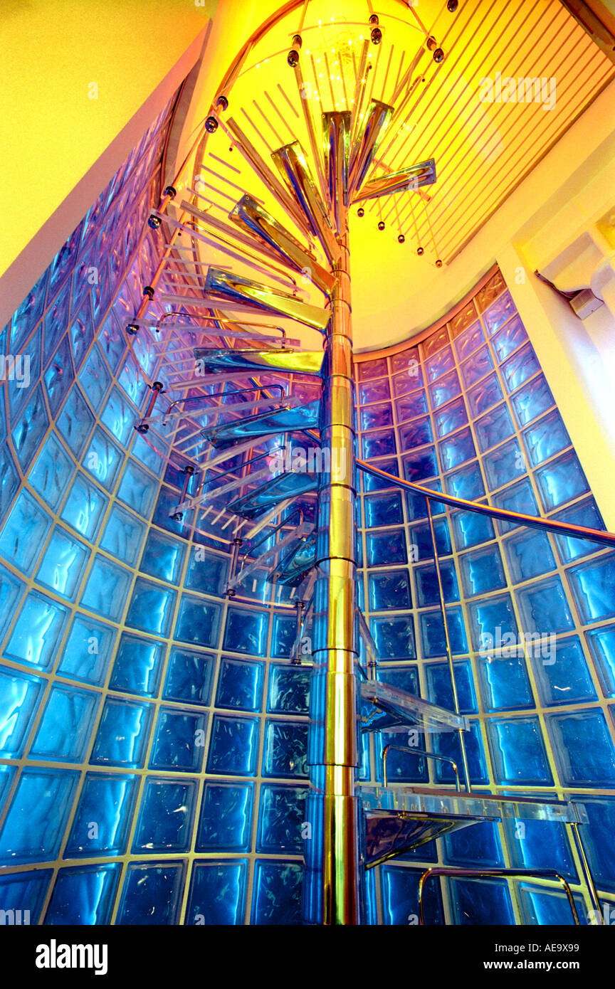 spiral staircase modern bright colourful light drama glass bricks coloured blue looking up at acute angle showing yellow ceiling Stock Photo