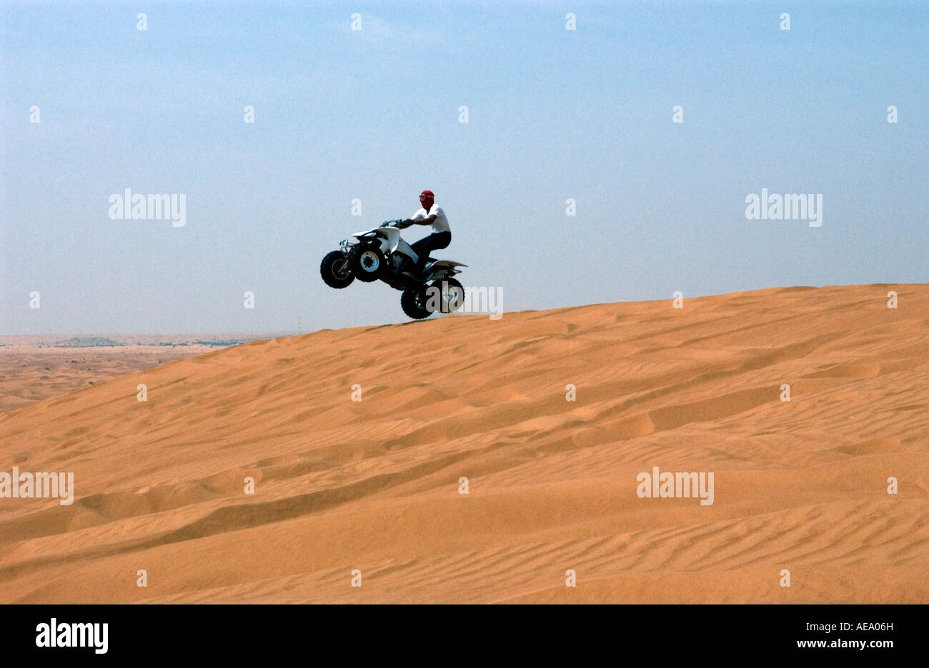 Quadbike doing a 'wheelie' off the edge of a Dubai desert dune Stock Photo