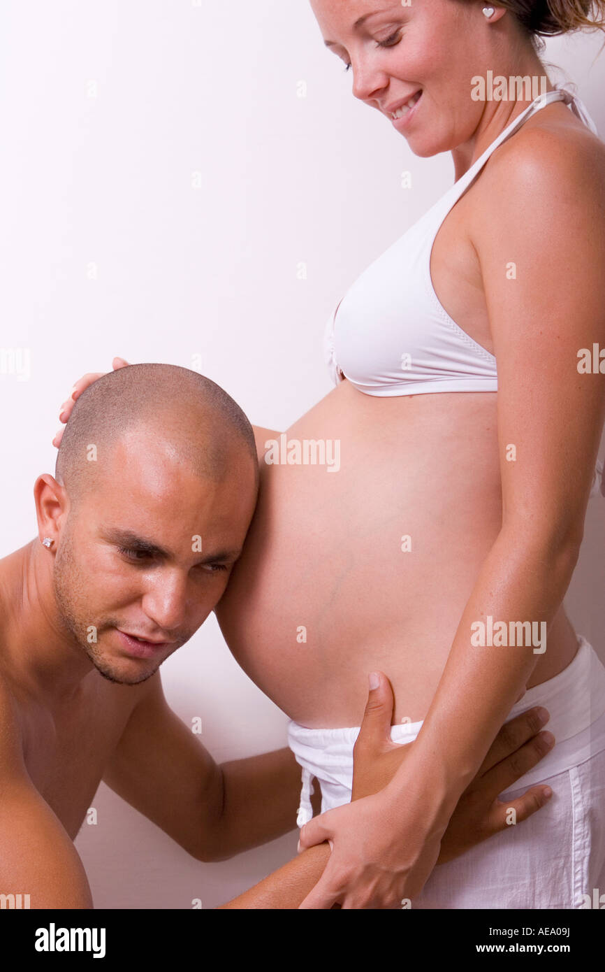 Man listening to pregnant woman s stomach Stock Photo