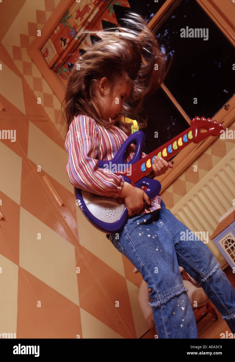 Little girl playing at being a pop rock star in her playroom Stock Photo