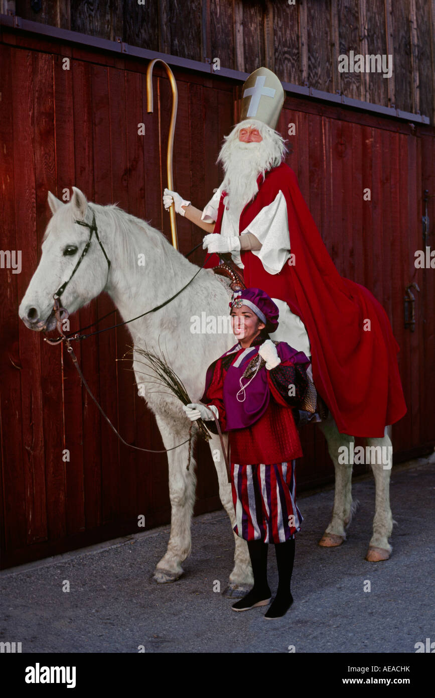 SAINT NICHOLAS mounted on a WHITE HORSE with a JESTER Stock Photo