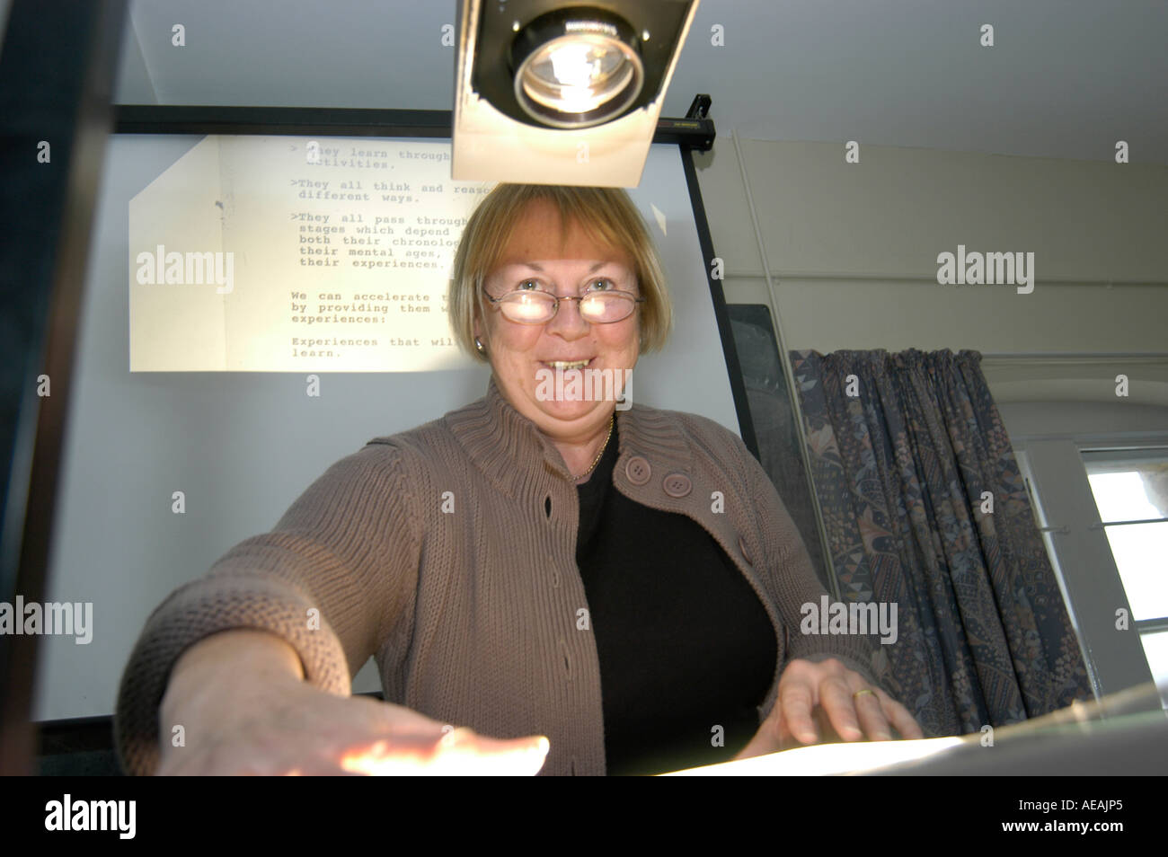 woman teacher using an overhead projector teaching her class