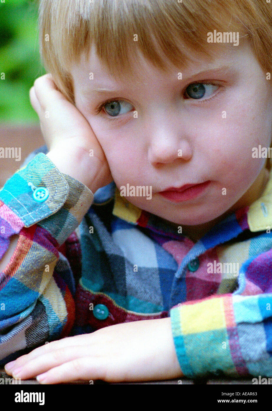 Young boy deep in thought wearing a chequered shirt Stock Photo