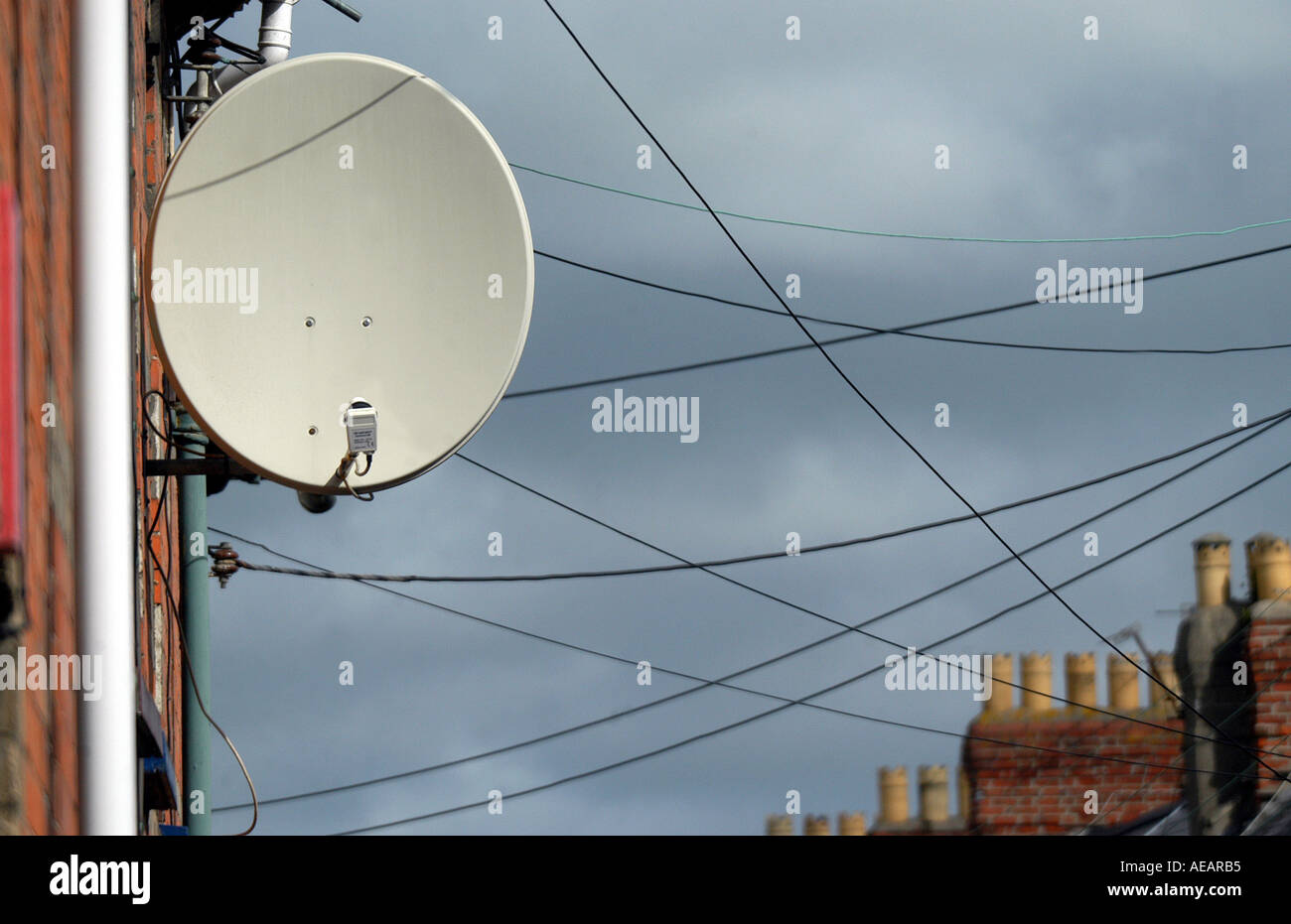A large satellite dish sat on the side of a house, with telephone wires