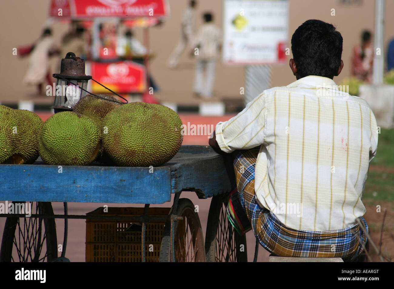 A man selling durian fruit stares into the distance at Marina Beach in