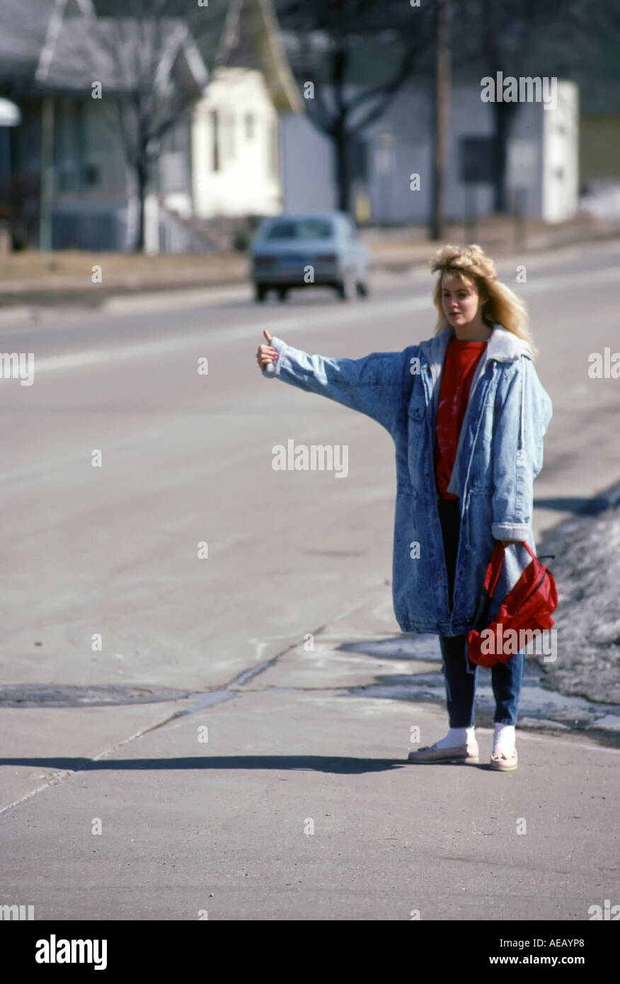 Teen female runaway from home hitch hikes on a highway looking for a free ride Stock Photo